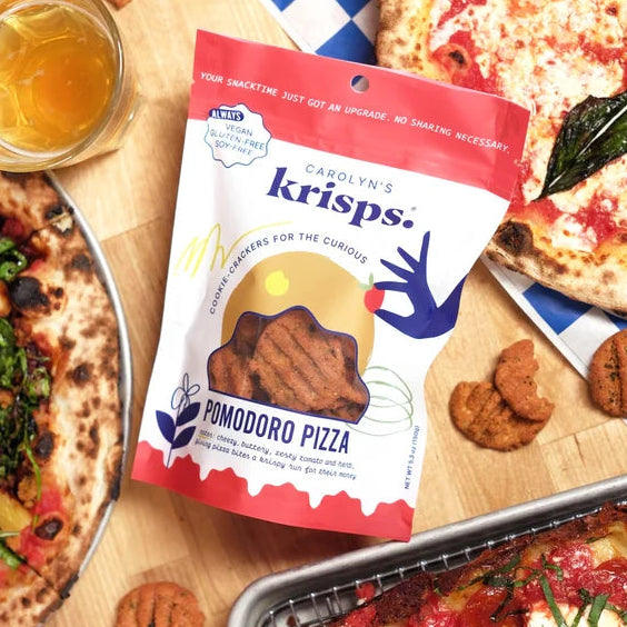 Pomodoro Pizza flavor of Carolyn's Krisps on a wooden table with numerous styles of pizza